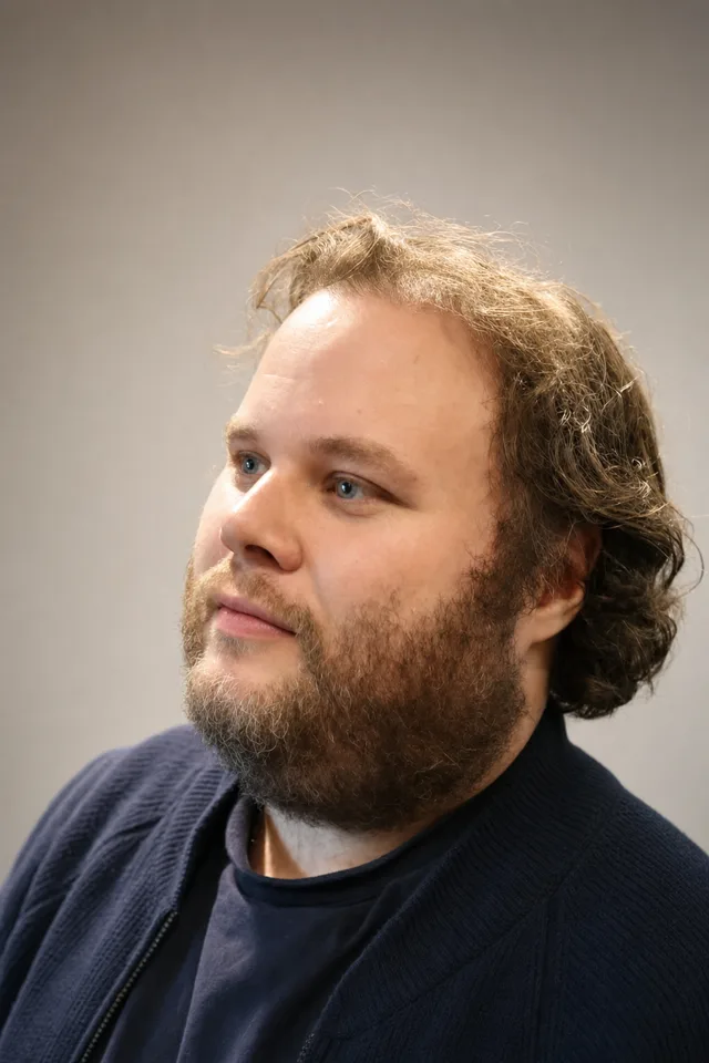 Portrait of Brad Hill — three-quarter view, navy knit jacket, looking thoughtfully to the left